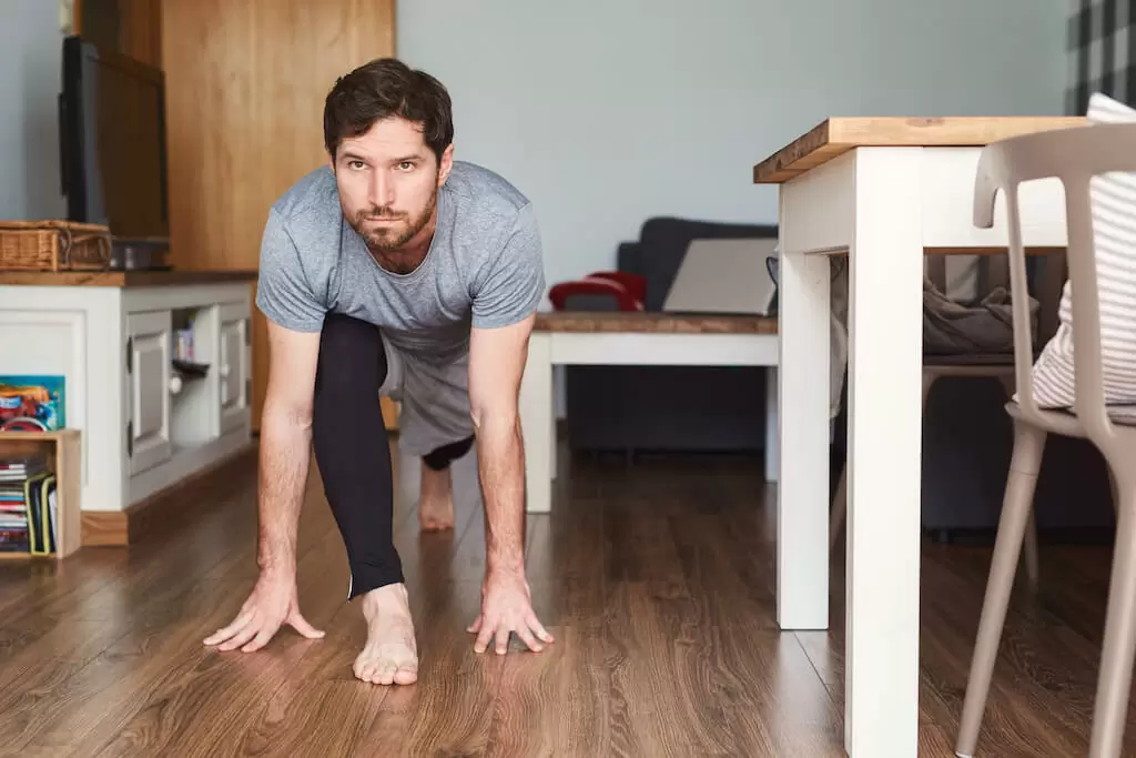 Fit young man in sportswear doing yoga at home